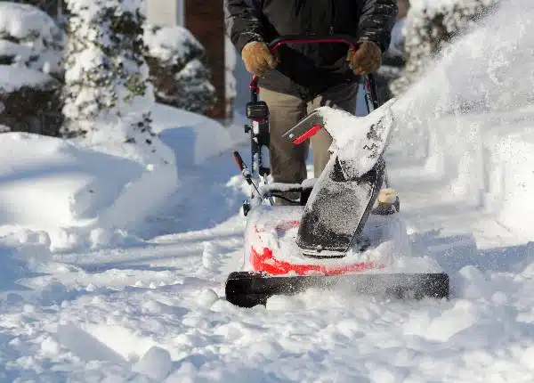 Unerkennbare Person betätigt Schneeräumgerät im Schnee