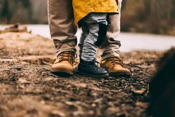 Kinderschuhe und Erwachsenenschuhe auf dem Boden im Wald